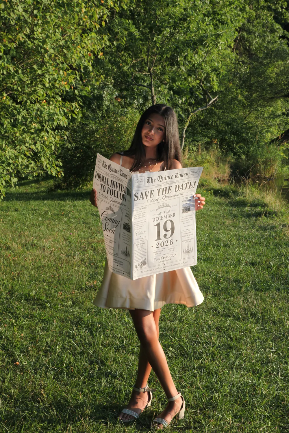 Celeste standing on the grass, holding the Save the Date newspaper open.