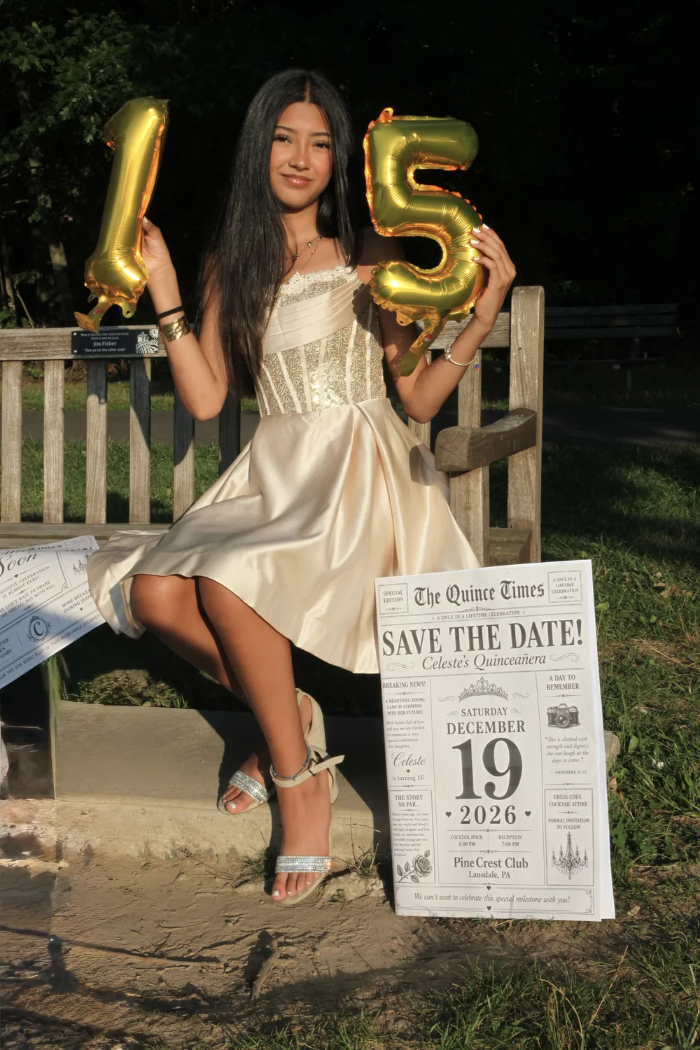 Celeste sitting on a wooden bench, holding up the gold balloons shaped like 1 and 5, with the Save the Date newspaper propped beside her.