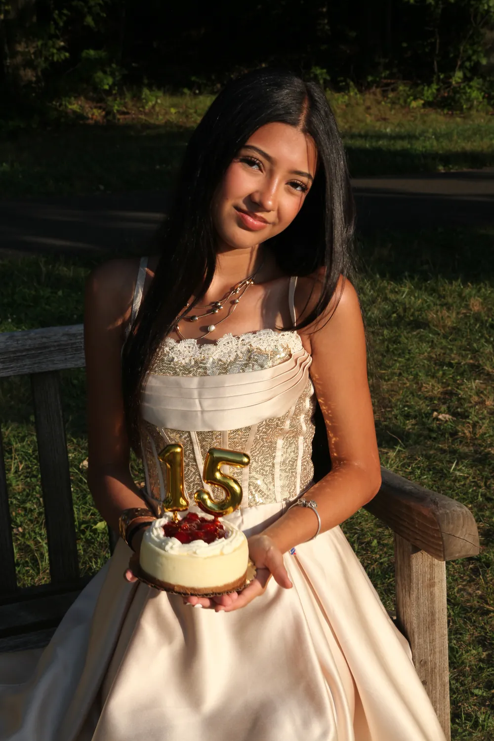 Celeste holding a small cake with gold candles shaped like 15.